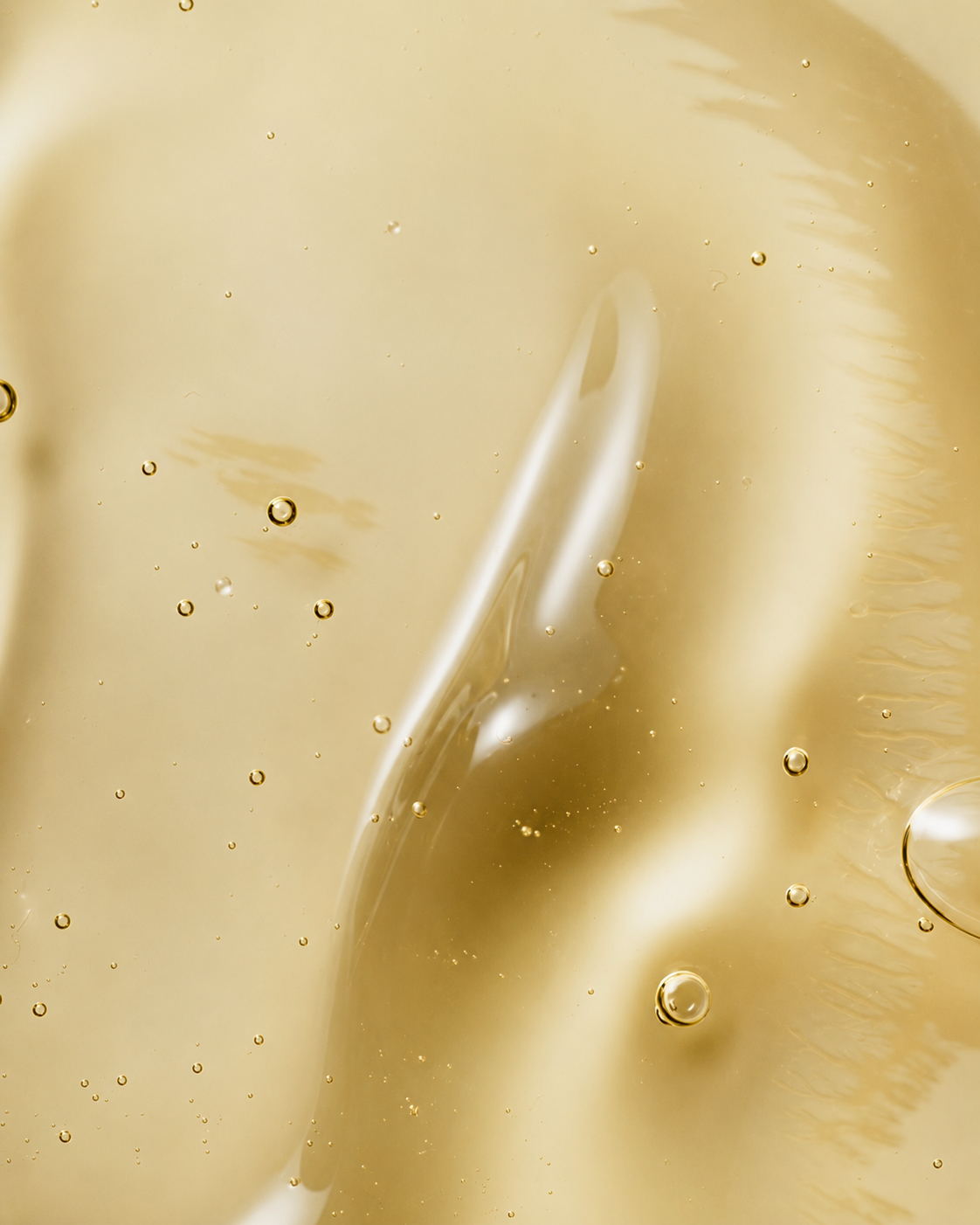 Macro photograph of a golden viscous serum with suspended air bubbles